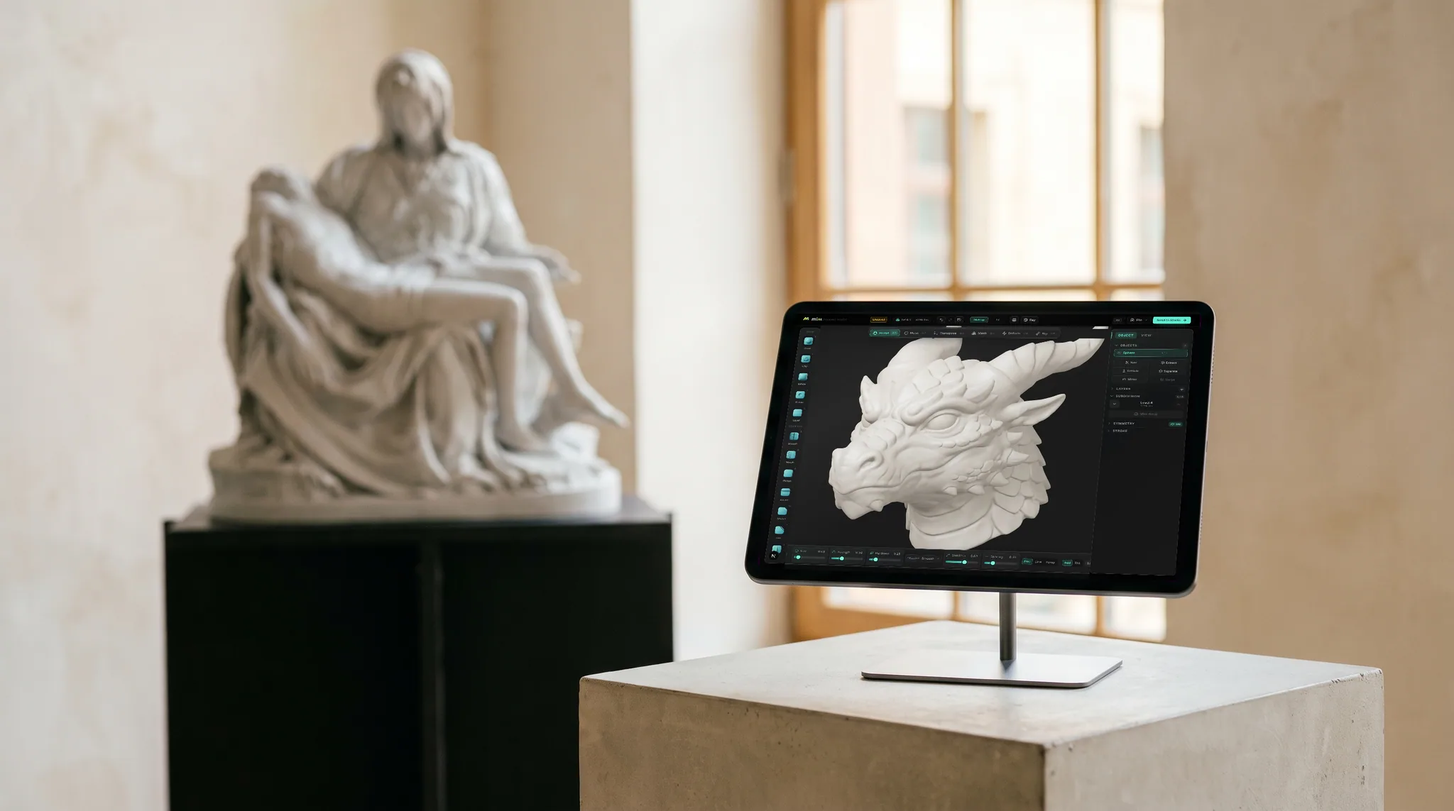 mixos Mold open on an iPad showing a horned dragon head sculpted in pale digital clay, on a plinth, with the real physical version of the same subject behind it.