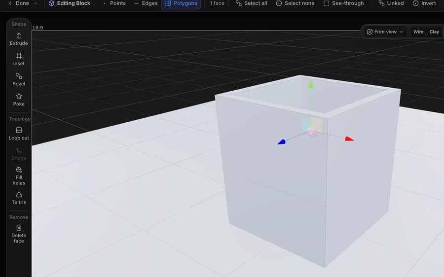 Bearbeiten eines Meshes in Studio: Polygon-Modus mit einer ausgewählten Fläche, die Befehle extrude, inset, bevel, loop cut und bridge in der Leiste, und eine Aussparung, die in den Block geschnitten wurde